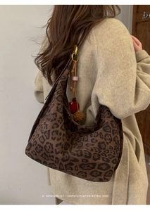 Detail of leopard print canvas tote bag with decorative pompom and long shoulder strap