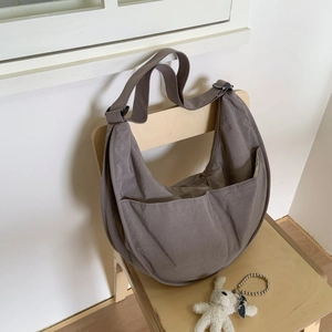 Taupe nylon crescent shoulder bag with wide adjustable strap on a chair