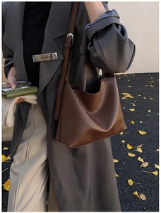 Detailed texture of dark brown lychee pattern leather on a stylish hobo shoulder bag