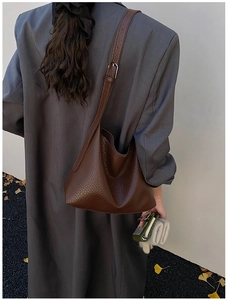 Deep brown litchi pattern leather tote bag shown from behind in a street style view