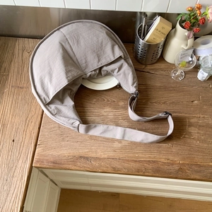 Detailed view of the gray nylon crescent shoulder bag on a rustic wooden table surface