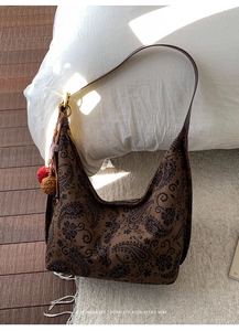 Detailed retro paisley pattern shoulder bag with faux fur pompom charm on a leather strap