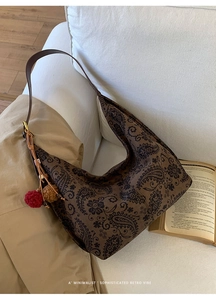 Detail of retro paisley pattern canvas tote bag with brown leather straps and pompom charms