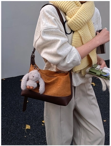 Detail of ginger suede pleated crossbody bag with brown leather base and plush bunny charm