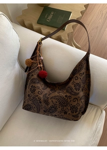 Retro brown paisley tote bag with leather straps and decorative tassel on fabric sofa