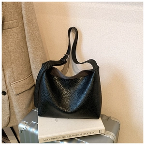 Close-up of black lychee texture leather tote bag with adjustable silver buckle strap
