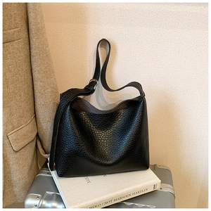Detailed macro view of black pebbled leather texture and silver buckle on hobo bag