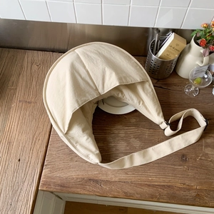 Overhead view of a beige nylon crescent shoulder bag on a wooden table setup