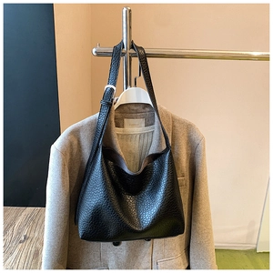 Detail of black pebbled leather hobo bag with adjustable silver buckle on a wide strap