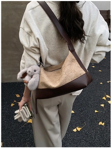 Detail of pleated beige crossbody bag with brown leather strap and bunny charm decor