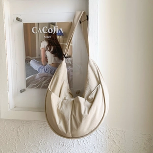 Detail of beige nylon crescent bag featuring a side pocket and adjustable shoulder strap