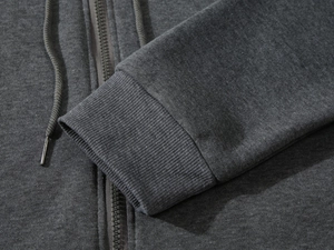 Macro shot of dark grey zip-up hoodie featuring ribbed cuffs and metal-tipped drawstrings