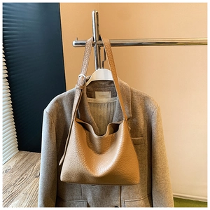 Detail of camel lychee leather tote bag with adjustable strap and silver metal buckle