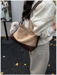 Detail of pleated beige fabric and brown leather shoulder bag with a cute bunny charm