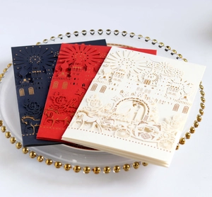 Detailed laser-cut wedding invitations featuring elegant castle designs in navy, red, and ivory