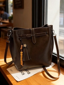 Sac seau vintage en similicuir marron foncé avec franges et perles à la lumière