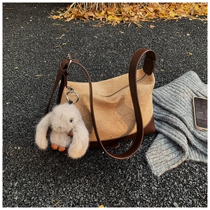 Detail of beige pleated shoulder bag with dark brown leather straps and plush bunny charm