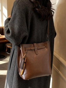 Sac seau vintage marron foncé avec franges et perles porté par un mannequin