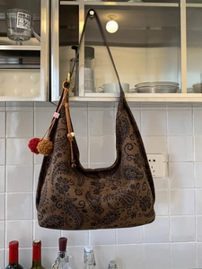 Vintage brown paisley tote bag with plush pom-pom charms in a retro casual style