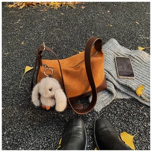 Detailed texture of dark brown pleated leather crossbody bag with cute plush rabbit charm