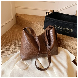 Detail of dark brown lychee grain leather shoulder bag with adjustable silver buckle strap