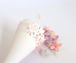 Detailed laser-cut hollow rose pattern on white wedding confetti cone with flower petals