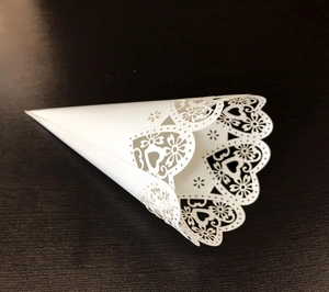 Macro shot of laser-cut heart lace pattern on white wedding petal cone holder