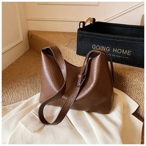 Close-up of dark brown leather texture and stitching on a large capacity tote bag