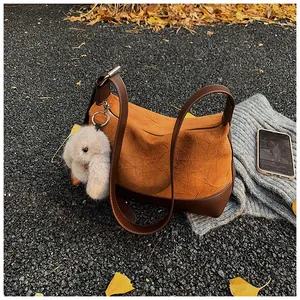 Detail of pleated orange dumpling bag with leather trim and plush rabbit keychain