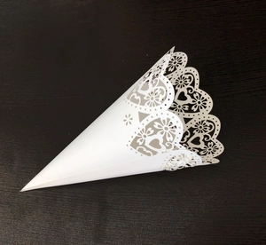 Macro view of white laser-cut confetti cone with heart patterns and lace edges