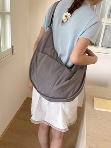 Deep grey large nylon crescent dumpling bag worn as a casual crossbody shoulder bag