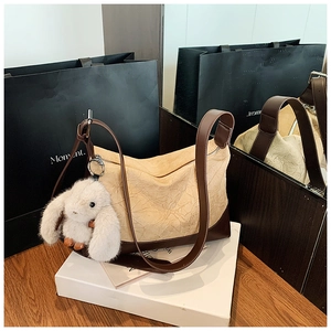 Detail of pleated shoulder bag with brown leather trim and cute plush bunny charm