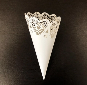 Detail of white laser-cut confetti cone with intricate heart and floral lace patterns