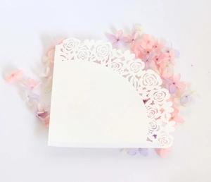 Close-up of laser cut white paper cone with rose pattern for wedding flower petals