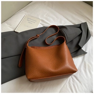 Detailed view of caramel brown leather bag with lychee texture and adjustable strap