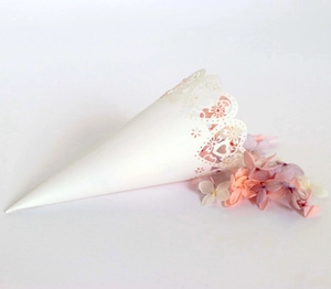 Macro detail of white laser-cut hollow heart paper cone for wedding flower petals