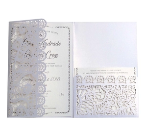 Detail of laser-cut wedding invitation with intricate lace floral pattern on pearl paper