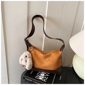 Detail of yellow pleated hobo bag with plush rabbit charm and brown leather strap