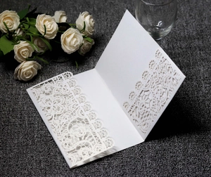 Detail of laser-cut white wedding invitation with elegant floral lace pattern