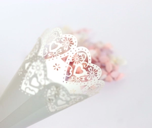 Detail of laser-cut white paper wedding confetti cone with elegant heart and lace patterns