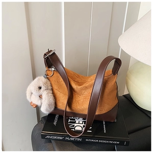 Detail of pleated ginger yellow faux leather texture with brown leather strap and bunny charm