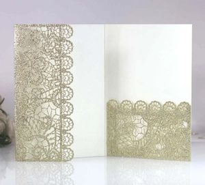 Detail of laser-cut lace floral pattern on gold glitter wedding invitation card cover