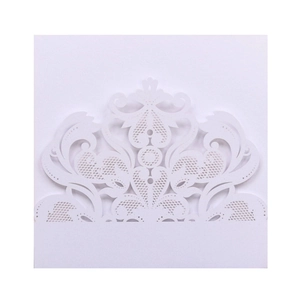 Close-up of intricate laser-cut floral lace patterns on white wedding invitation card