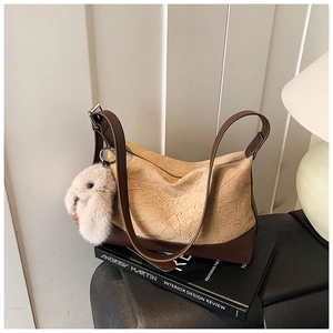 Close-up of pleated khaki faux leather bag with brown trim and plush rabbit keychain