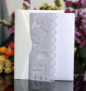 Macro detail of laser-cut lace wedding invitation with pearl shimmer and envelope