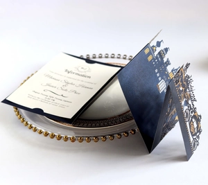 Detailed laser-cut navy wedding invitation featuring a gold foil castle and carriage motif