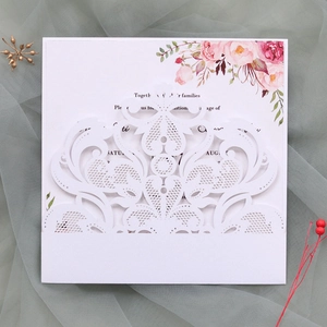 Detail of white laser-cut lace wedding invitation with floral insert and damask pattern