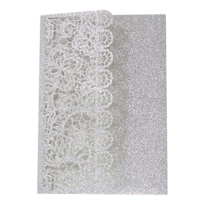 Macro shot of silver glitter laser-cut floral lace details on wedding invitation card