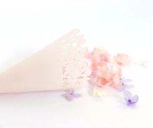 Detail view of laser-cut rose paper confetti cone for wedding decorations with floral edges