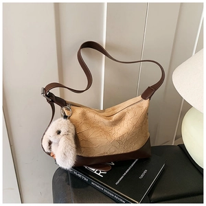Detailed view of the pleated texture and rabbit charm on a stylish brown crossbody bag